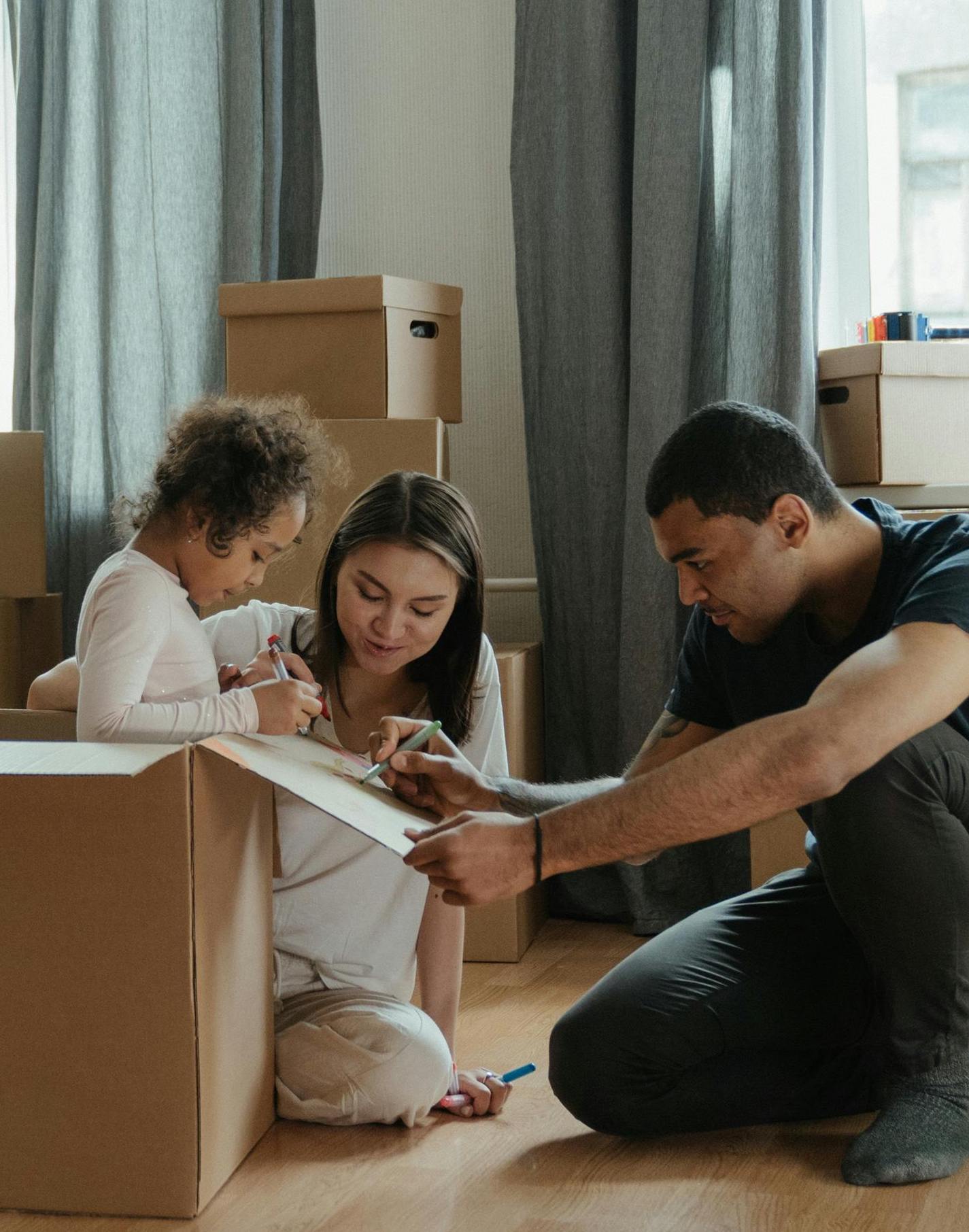 Un couple et un enfant qui ouvrent des boites de déménagement
