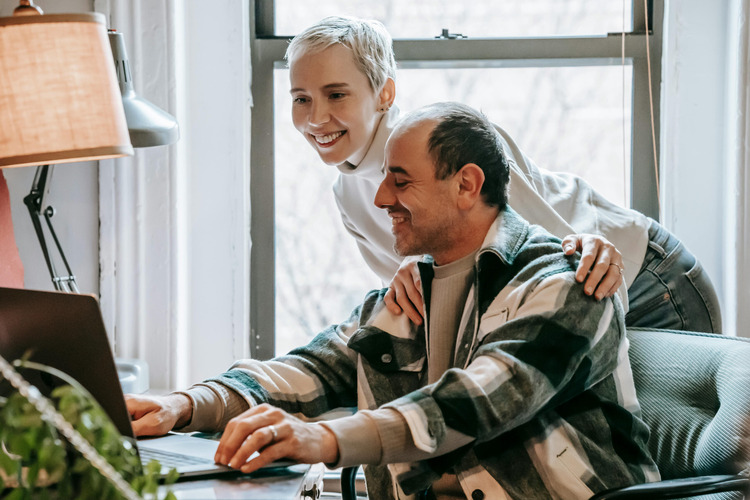 Un couple qui sourit devant l'ordinateur